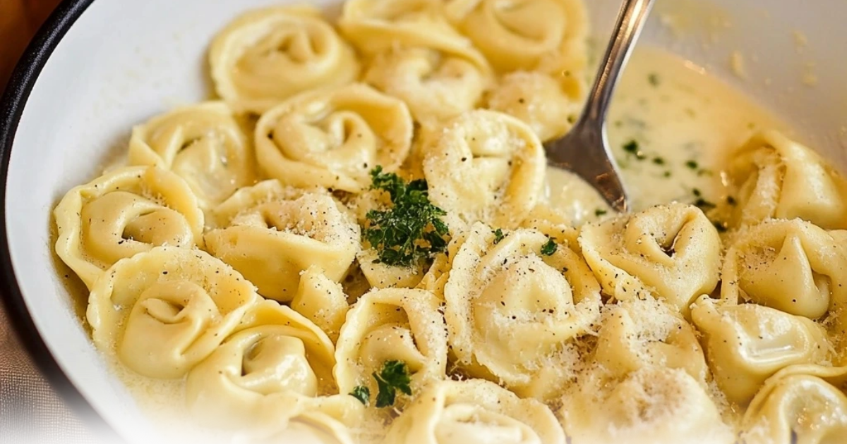 Can-you-eat-cold-cheese-tortellini – Cheese tortellini served in a creamy sauce, garnished with fresh parsley and black pepper.